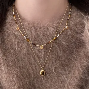 Elegant double-layered gold necklace with tiger eye stone pendant on a fuzzy sweater