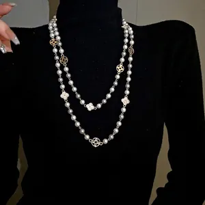 Elegant long vintage pearl necklace with sparkling crystal flower charms on black sweater