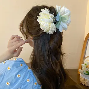 Close-up detail of a cream fabric flower hair claw clip elegantly worn on a wavy half-up hairstyle