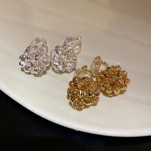 Detailed view of 18k gold plated flower cluster clip-on earrings on ceramic plate