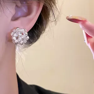 Close-up view of elegant silver-tone floral cluster clip-on earring worn on the ear