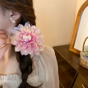 Detailed macro view of a large pink fabric flower hair clip worn on a braided hairstyle