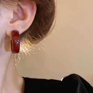 Detail of vintage burgundy enamel hoop earrings with glossy finish and elegant silver needle