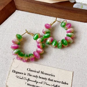 Detalle de pendientes de aro con cuentas de resina rosa y verde en estilo vintage