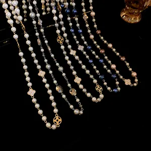 Close-up of elegant long pearl necklaces with sparkling clover and floral charms
