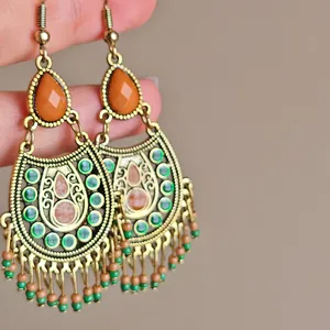 Close-up of Bohemian retro drop earrings with orange beads and green tassel details