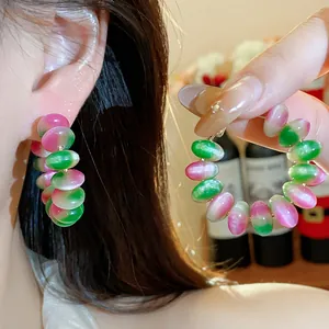 Primer plano detallado de pendientes de aro con cuentas de resina rosa y verde y plata