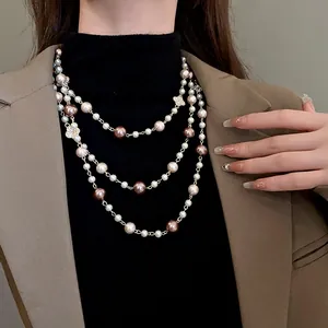 Detail of vintage layered pearl necklace with rhinestone flowers on model's blazer