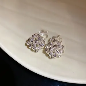 Close-up detail of silver floral cluster clip-on earrings with textured finish.