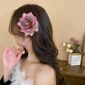 Detailed view of an elegant pink fabric flower hair clip worn on wavy brunette hair