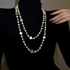 Close-up detail of vintage long pearl necklace with crystal floral motifs and gold finish.