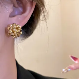 Detailed view of elegant 18k gold plated round flower cluster stud earrings worn on ear