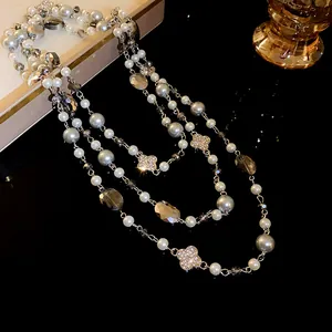 Close-up of multi-layer long necklace with pearls and rhinestone flower charms.