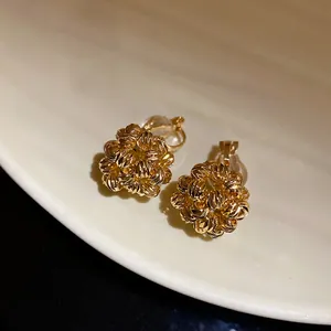 Close-up of 18k gold plated flower cluster clip-on earrings with textured bead details