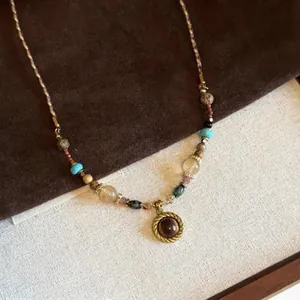 Close-up of a vintage tiger eye pendant necklace with colorful beads and woven cord.