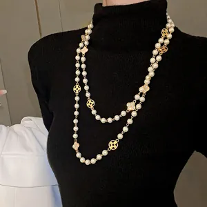 Elegant long pearl necklace with rhinestone flower charms styled over a black sweater