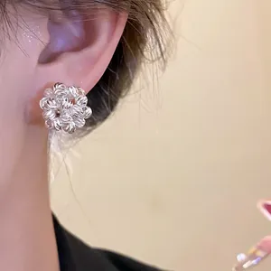 Close-up detail of a minimalist 18k gold plated flower cluster earring on an ear