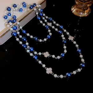Close-up of elegant blue and white pearls with sparkling rhinestone clover charms