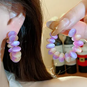 Detalle de pendientes de aro con cuentas de resina degradado púrpura en modelo.