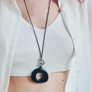 Close-up of a minimalist black resin hollow circle pendant on a leather cord.