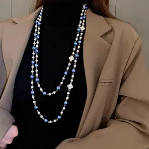 Close-up of a double-layer vintage pearl necklace featuring clover charms worn on a model