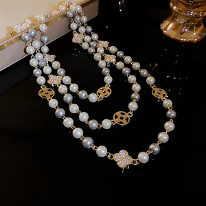 Detail of a vintage long pearl necklace featuring diamond flower charms and grey pearls.