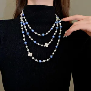 Detailed view of triple-layer pearl necklace with sparkling flower pendants on black