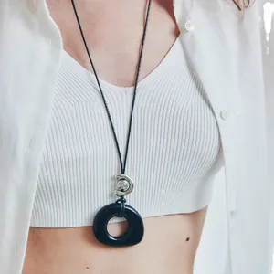 Minimalist black resin hollow round pendant necklace with leather cord shown on a model