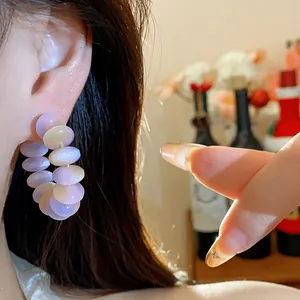 Primer plano detallado de elegantes pendientes de aro con cuentas de resina púrpura