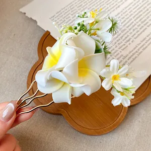 Detailed view of handmade frangipani flower hair fork with wavy gold metal design