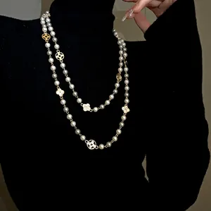 Close-up of elegant double-strand long pearl necklace featuring rhinestone flower charms