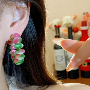 Detalle de un pendiente redondo de cuentas de resina rosa y verde estilo dopamina