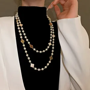 Close-up of vintage long pearl necklace with diamond-encrusted flower charms for women