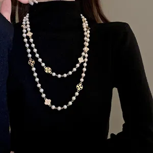 Elegant long pearl necklace with rhinestone flower charms styled on a black sweater.