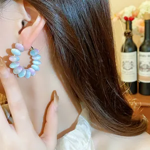 Primer plano de pendientes de aro con cuentas de resina de colores y aguja de plata