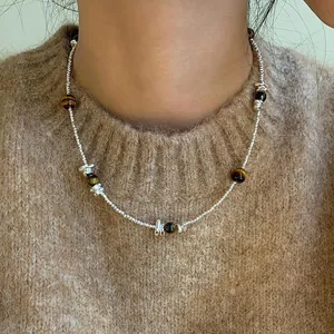 Detailed close-up of a women's tiger eye beaded necklace worn over a brown knit sweater