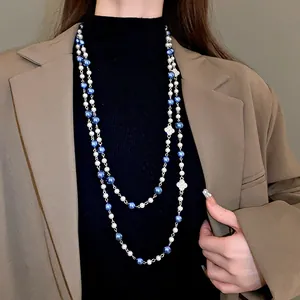 Macro view of a long double-layered pearl necklace featuring rhinestone flower charms
