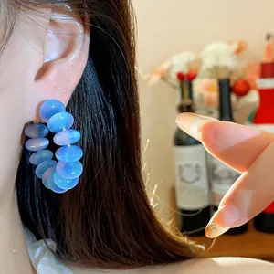 Primer plano detallado de aretes de aro de cuentas de resina azul usados