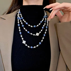 Triple-layer pearl sweater chain with blue accents and sparkling flower pendants