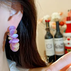 Detalle de pendientes de aro de cuentas de resina púrpura estilo dopamina en oreja