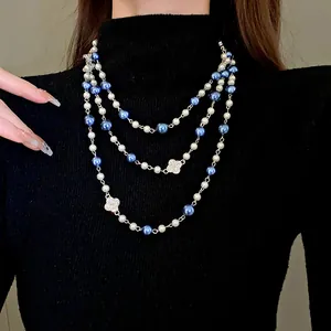 Detailed view of elegant multi-layered pearl necklace with rhinestone flower charms on black