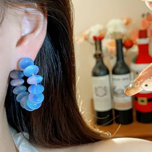 Primer plano de pendientes de aro con cuentas de resina azul en una modelo elegante