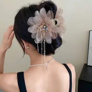 Elegant chiffon flower hair claw clip with long metallic tassels worn by a model.