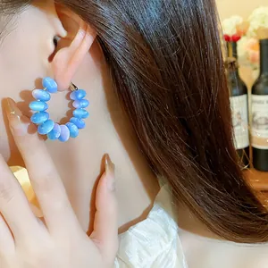 Detalle de elegantes pendientes de aro con cuentas de resina azul usados por una modelo