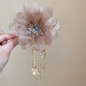 Close-up of elegant chiffon flower hair claw clip with long tassels and rhinestones