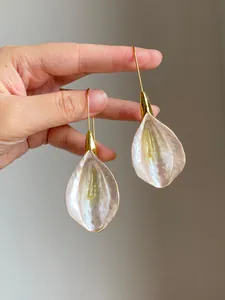 Detailed macro shot of pearlescent petal drop earrings with elegant gold hooks
