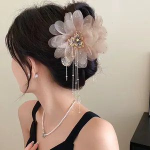 Detailed view of an elegant chiffon flower hair claw clip with golden tassels