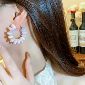 Primer plano de una modelo con elegantes pendientes de aro de resina con degradado
