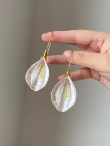 Detailed view of elegant white petal drop earrings with gold hooks for a vintage look