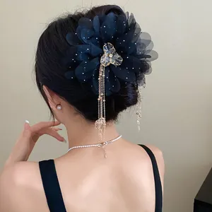 Elegant black chiffon flower hair claw clip with golden tassels on a woman's bun